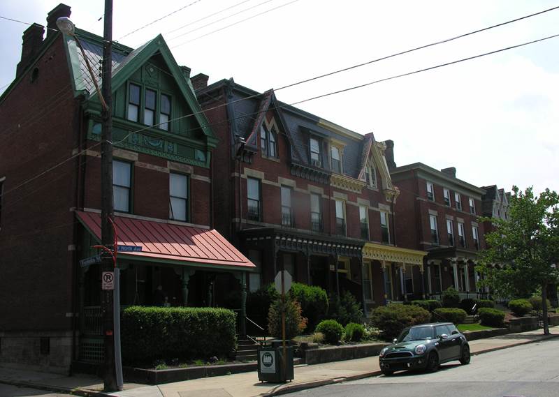 Row of 3-story brick houses with front porches.