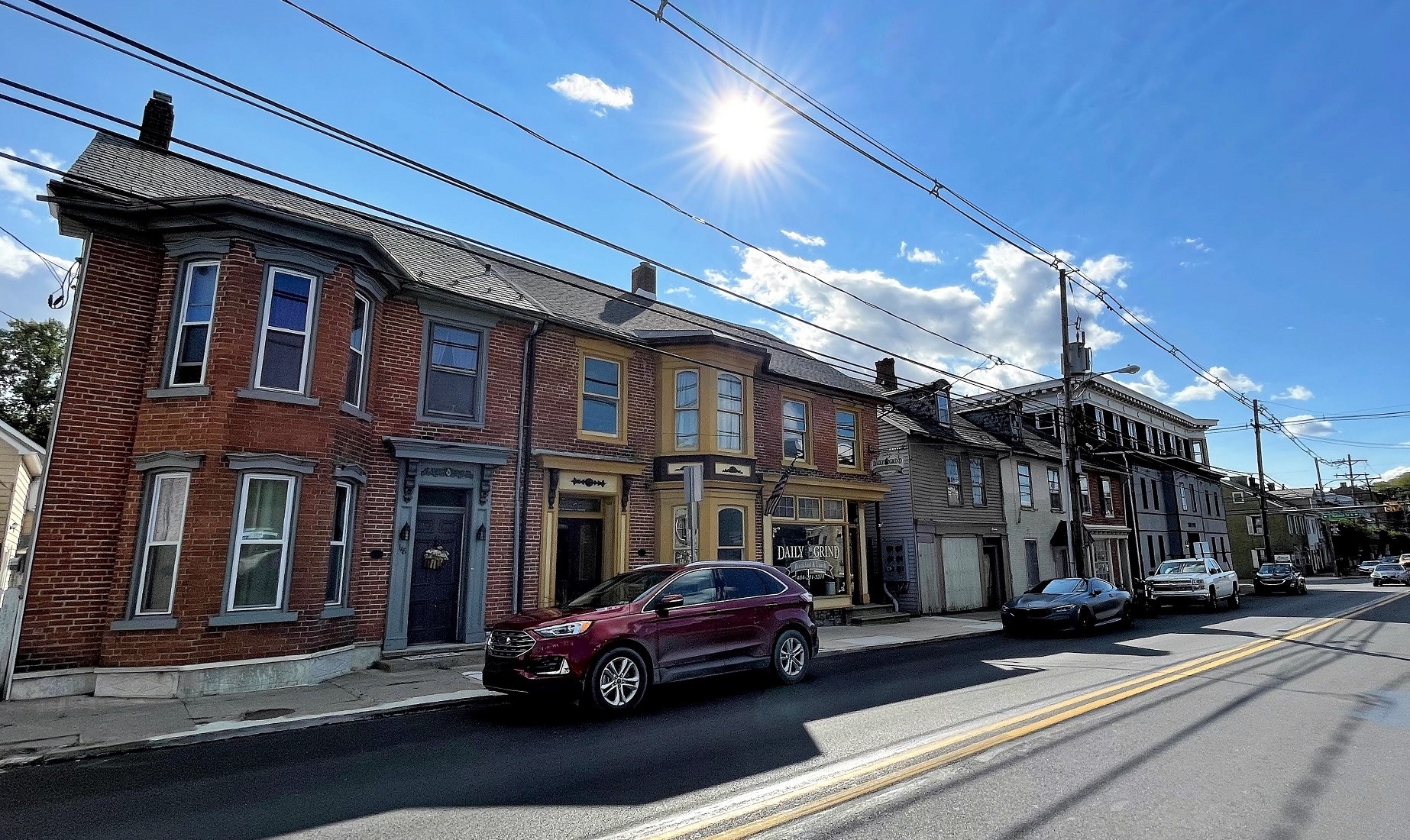 Row of two-story brick buildings along a paved street in a town.