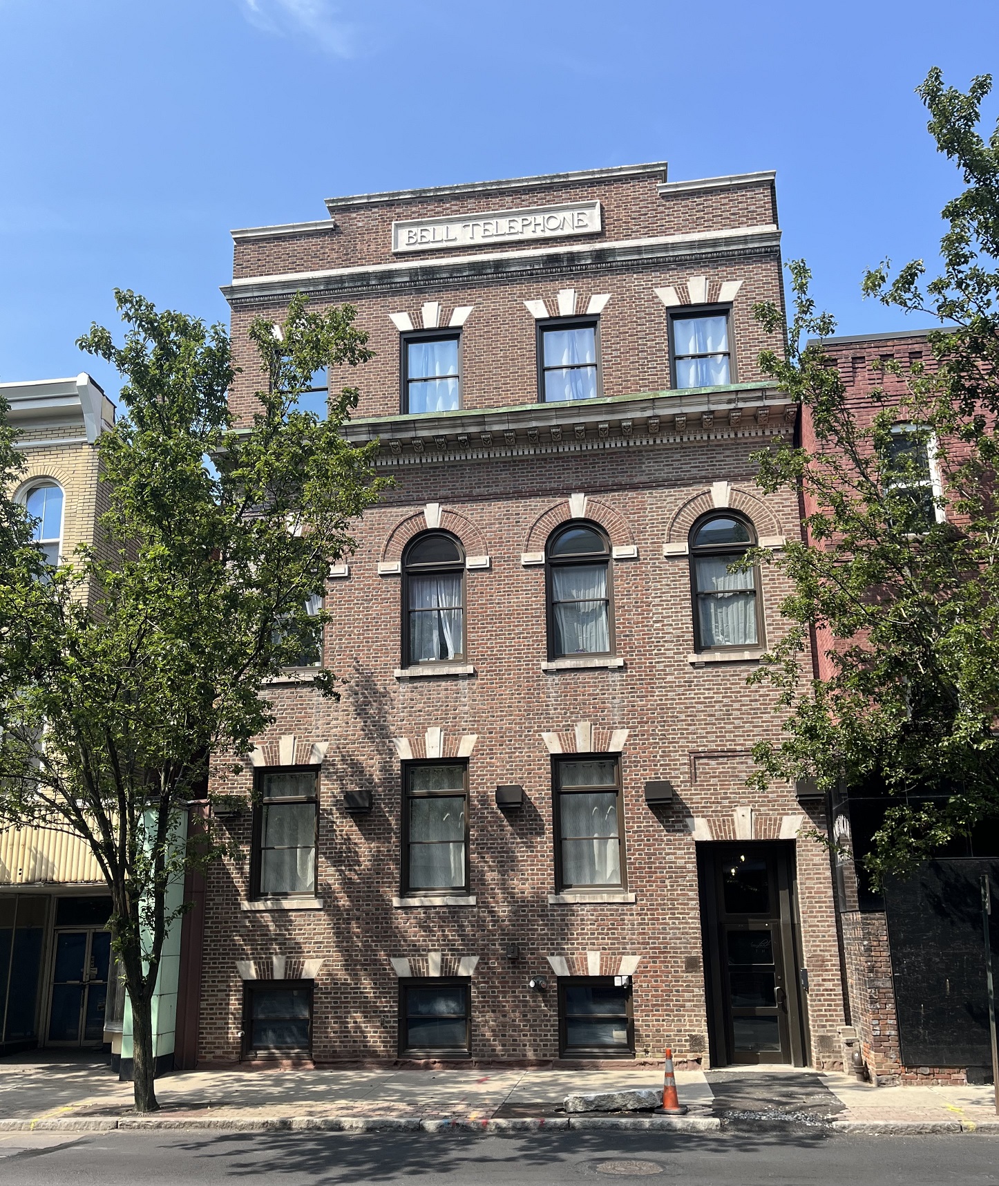 Four-story brick building with windows on each floor in the middle of an urban block.