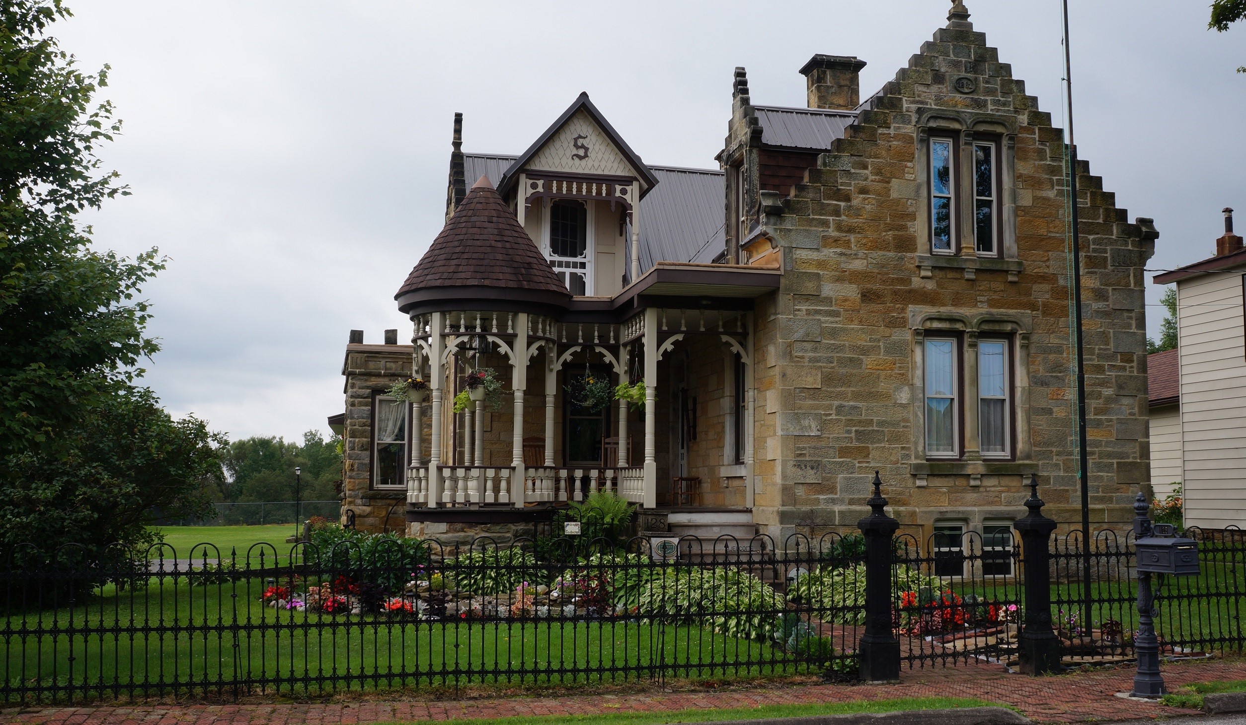 Small stone house with wood porch and gable roofs.