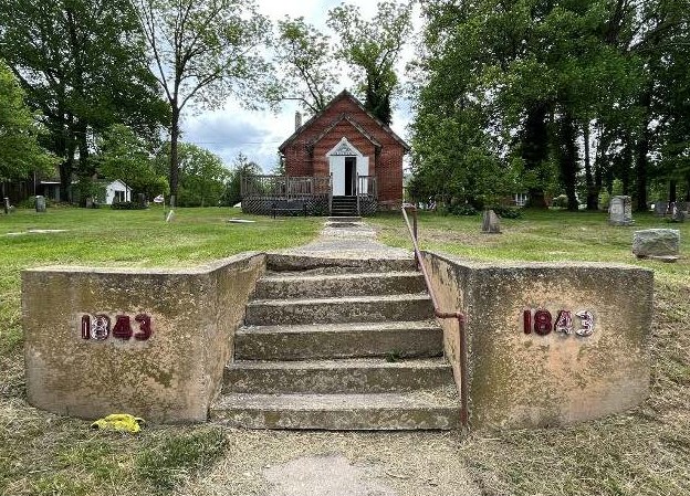 Small brick church set in cemetery.