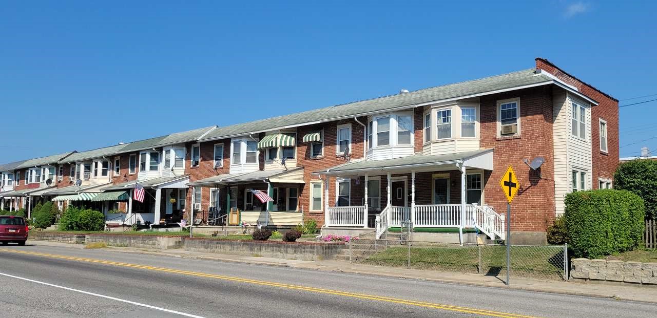 Row of connected two-story brick homes along a paved street.