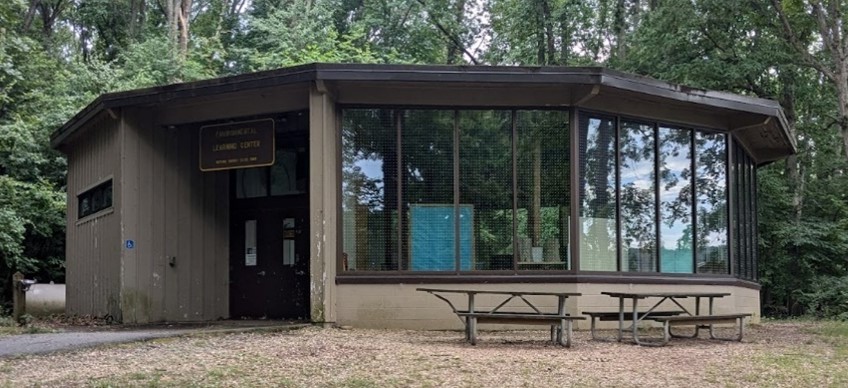 Round building with large windows in forested area.