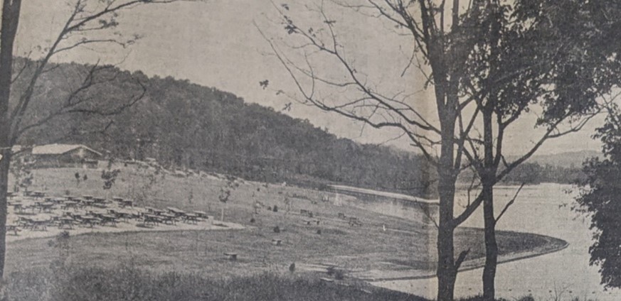 People on grass next to water.