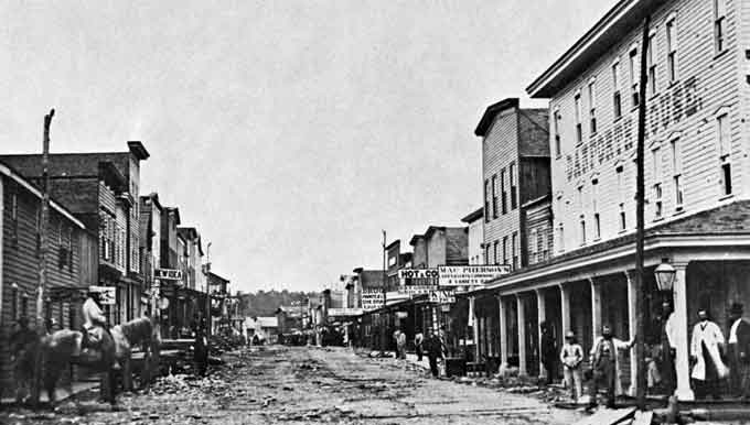 Old wood buildings along both sides of a dirt street.