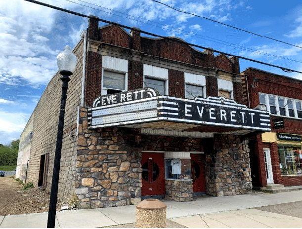 Two story brick building with stone at first floor and large windows on second floor above a large marquee.