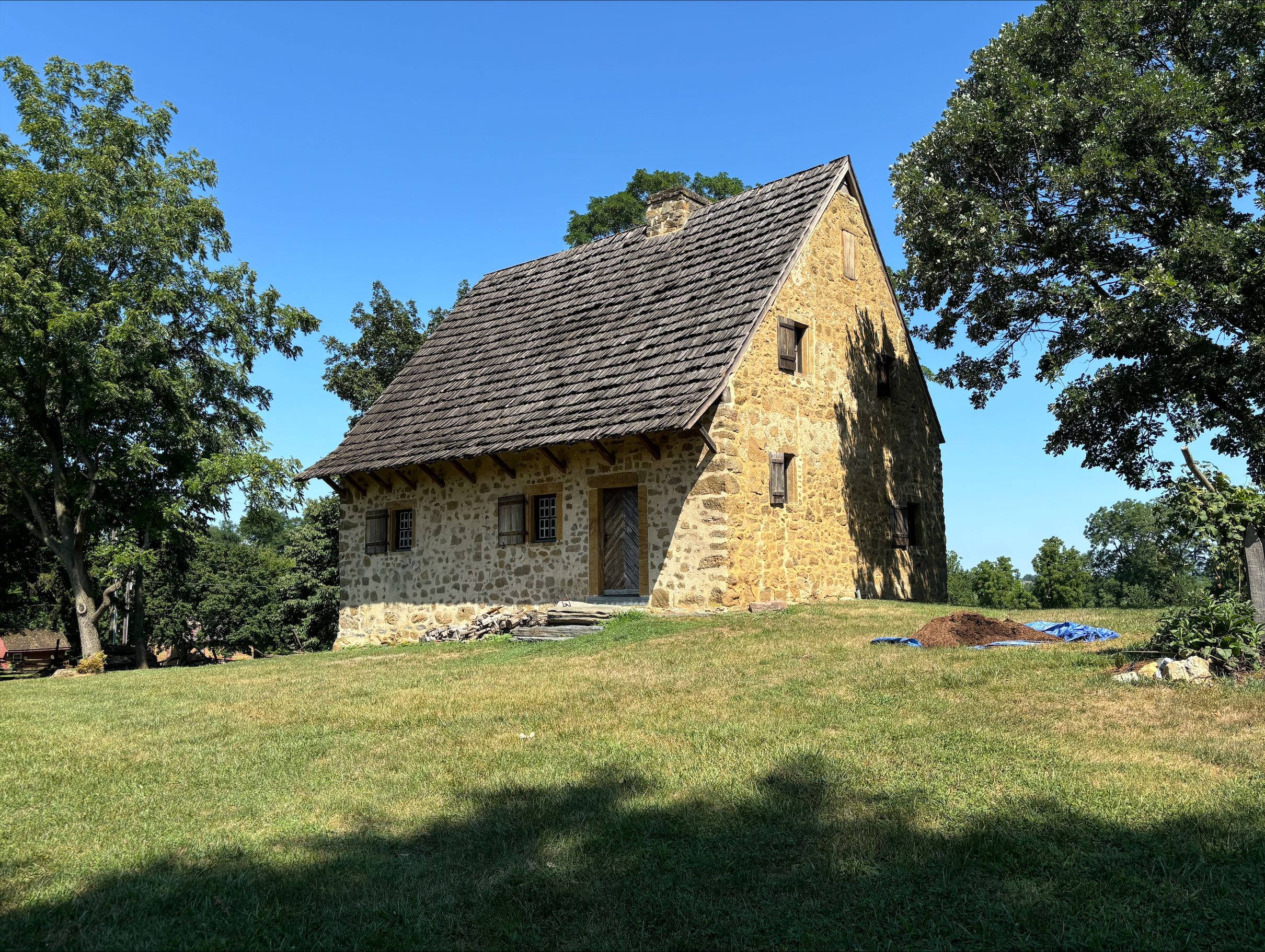 Small stone house with steep roof surrounded by grass.