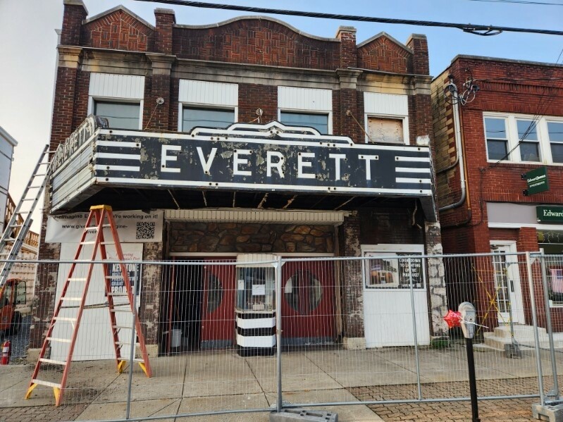 Two story brick building surrounded by construction fencing and ladders.