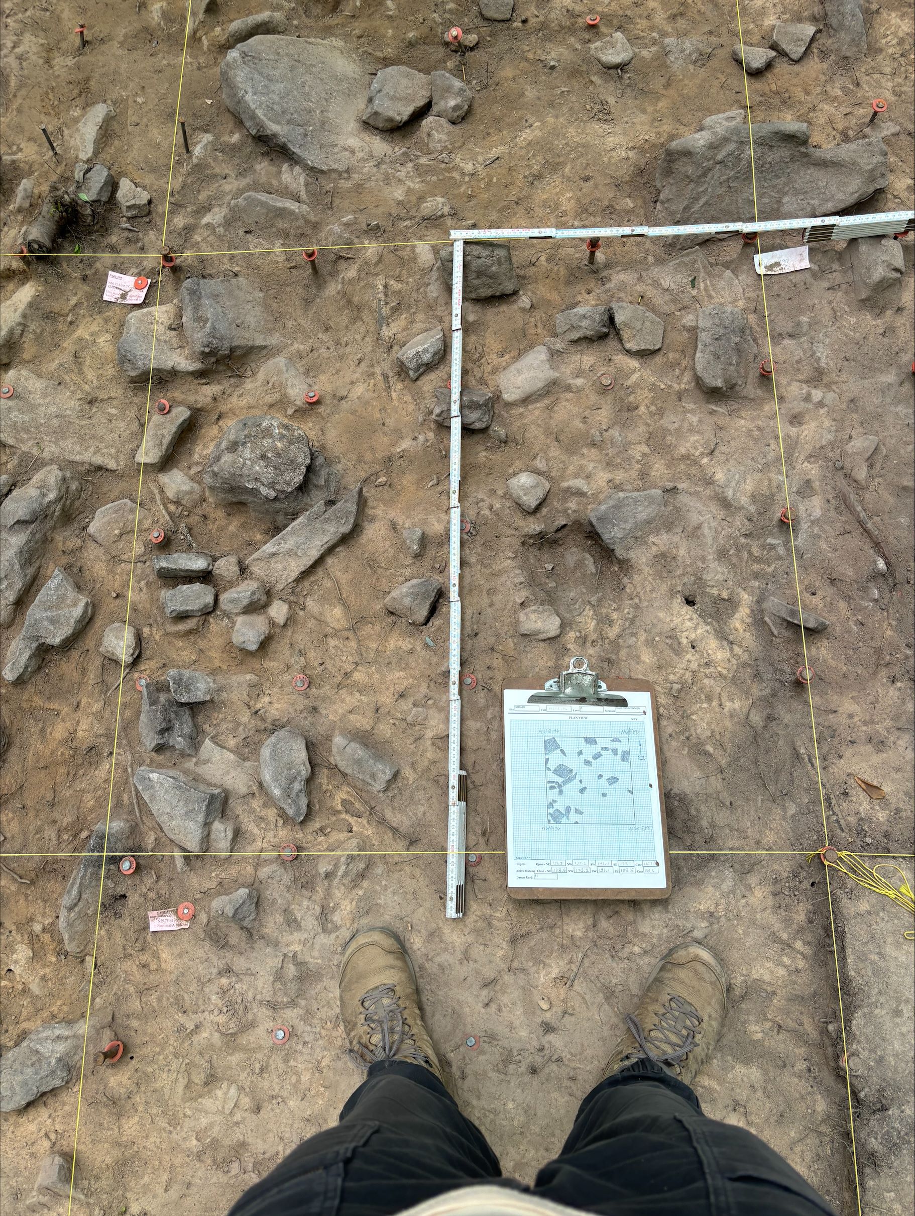 Person standing over bed of rocks and measuring tools.