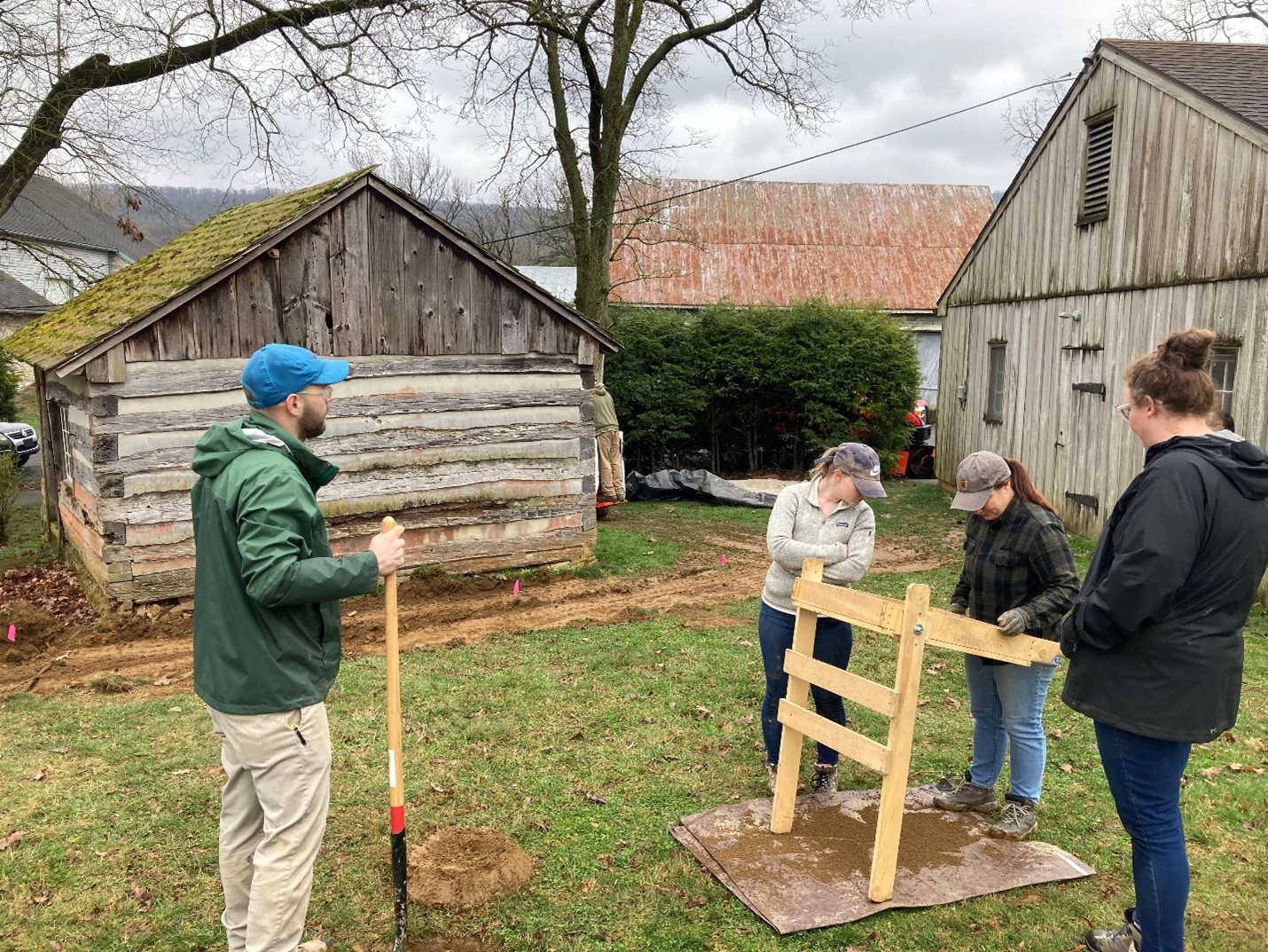 Four people standing outside in poor weather with wood equipment.