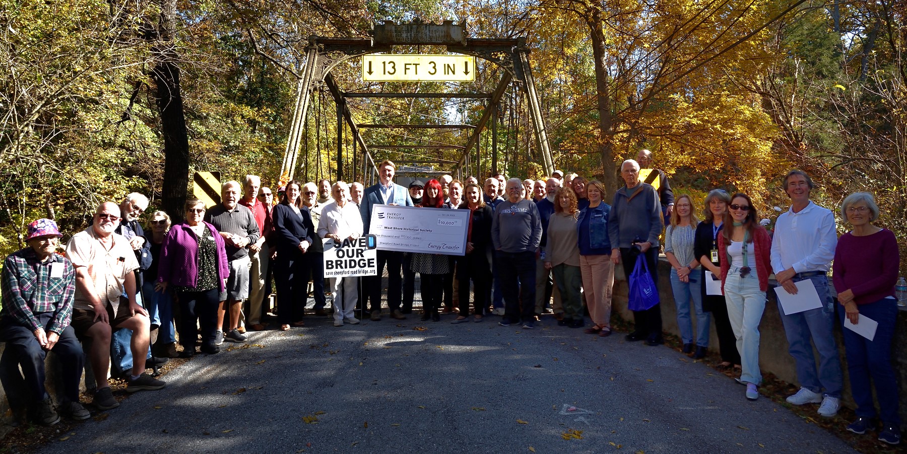 Large group of people standing in front of a bridge.