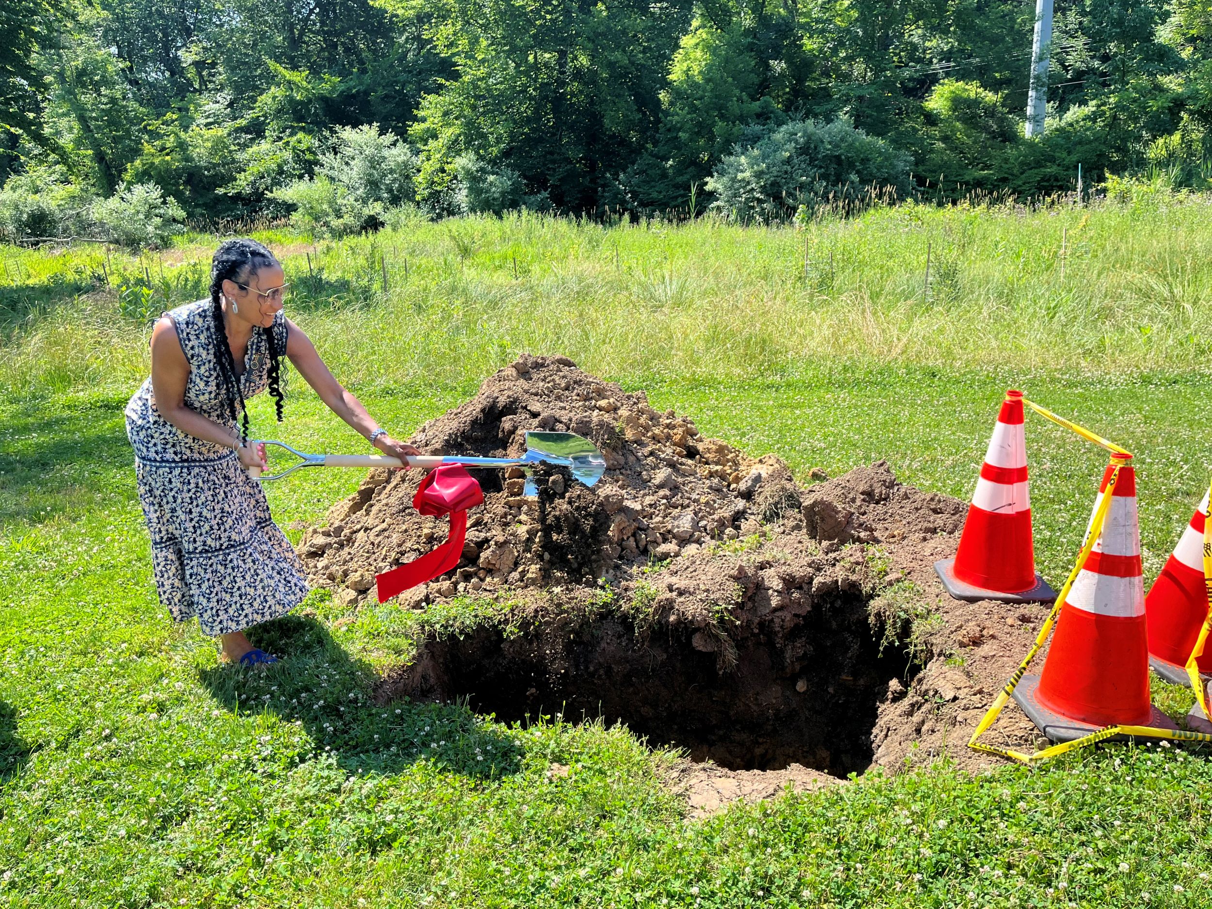 Woman shovels dirt into a hole in the ground.