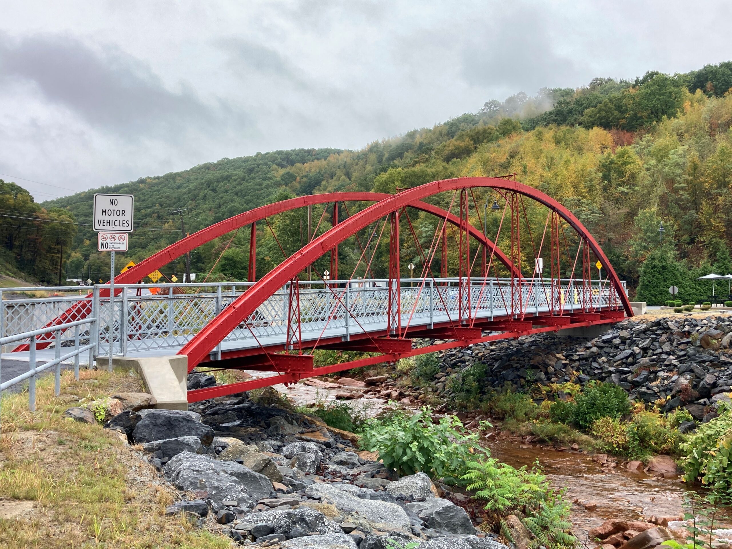 Red metal bridge over a stream.