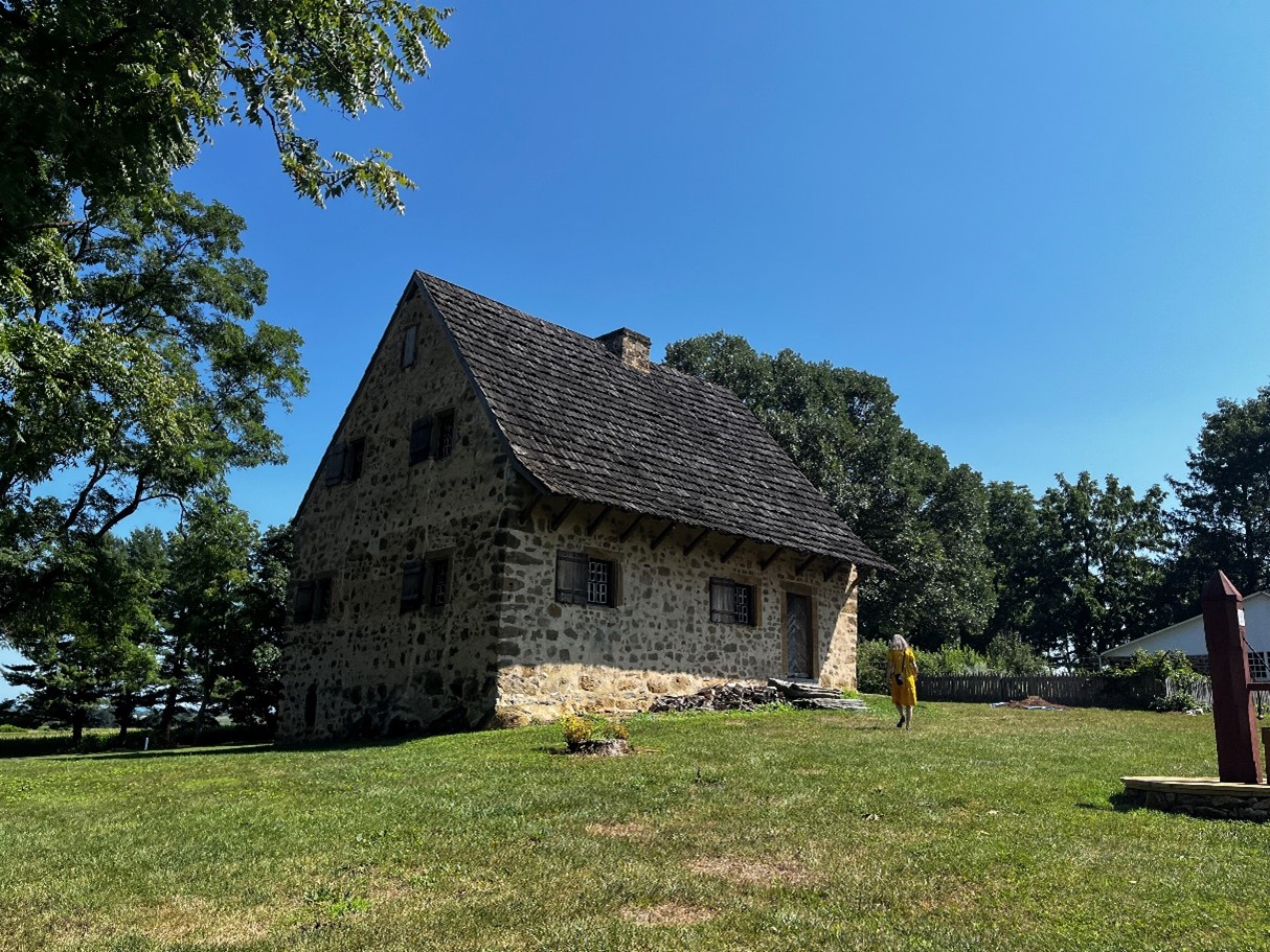 Small stone house with steep roof surrounded by grass.