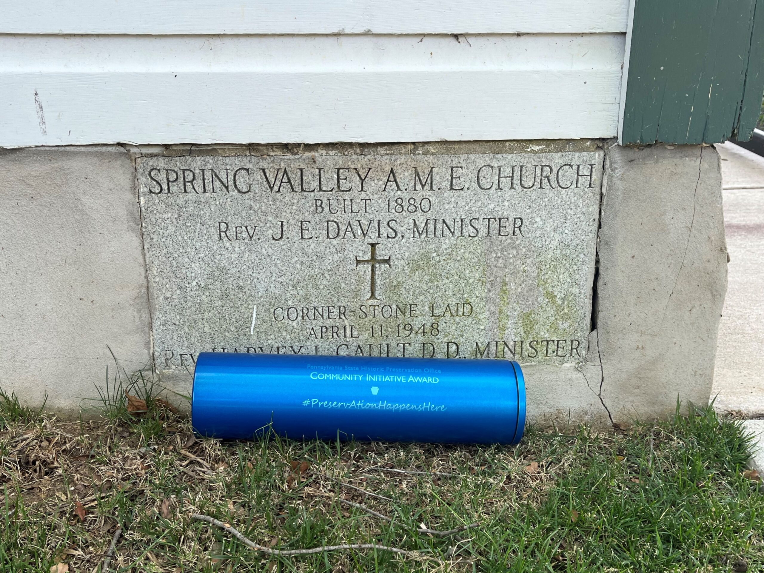 Metal cylinder in front of stone date stone.