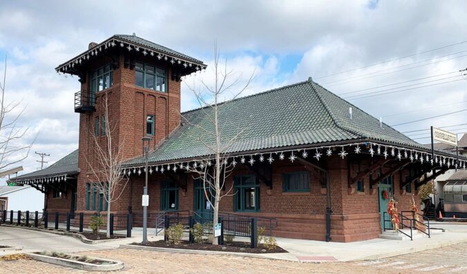 One-story brick building with steep tile roof and large square roof.