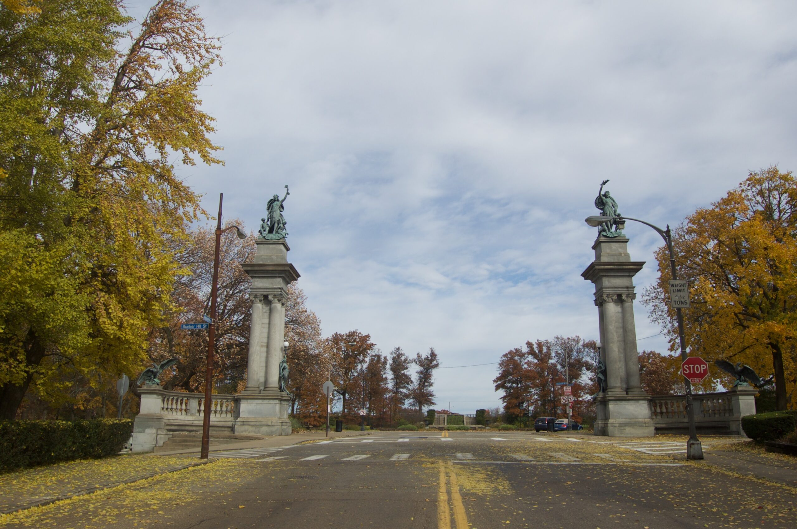 Two large columns with statues on either side of a two-lane road.