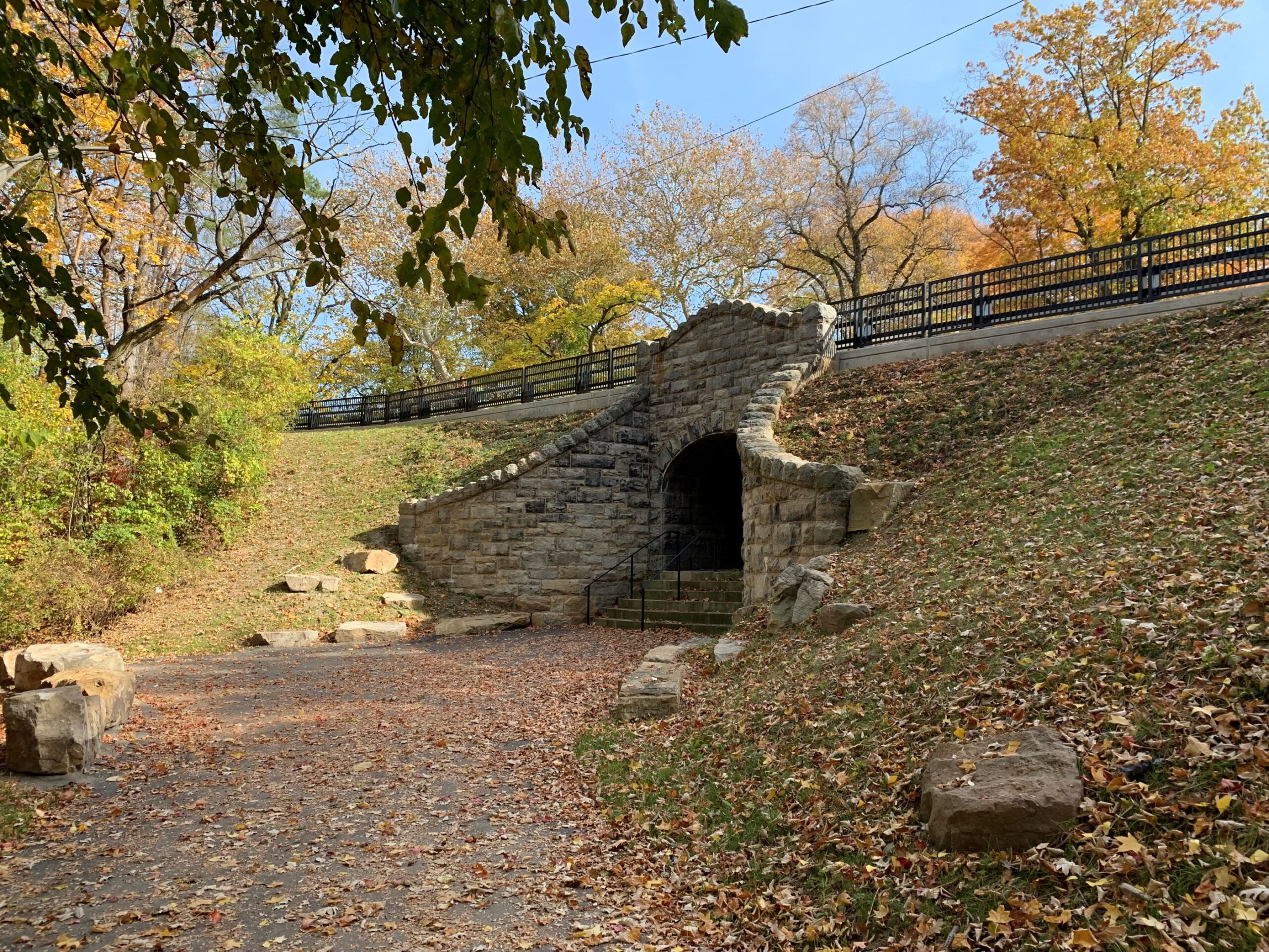 Elaborate stone walls surround a tunnel opening. A paved path and steps lead to the tunnel.