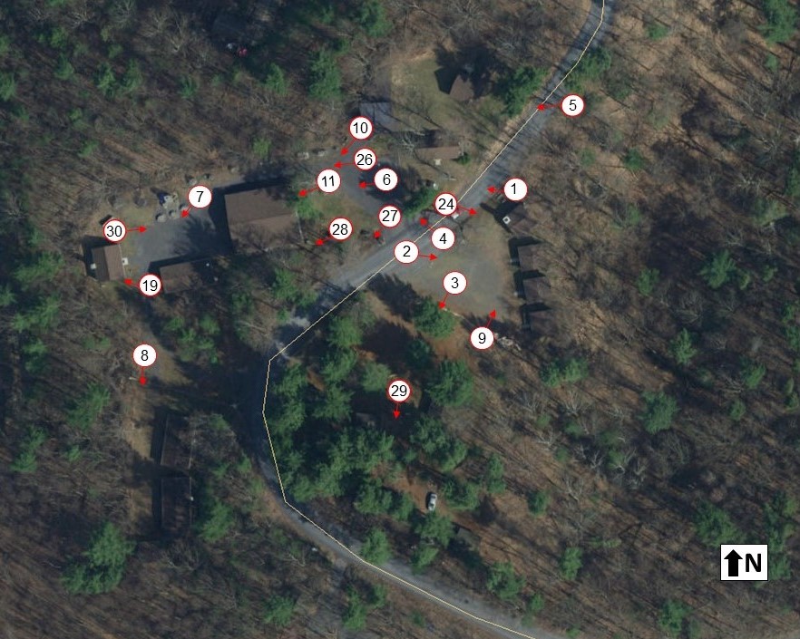 Aerial photograph of wooded area and buildings with small white circles with numbers scattered across.