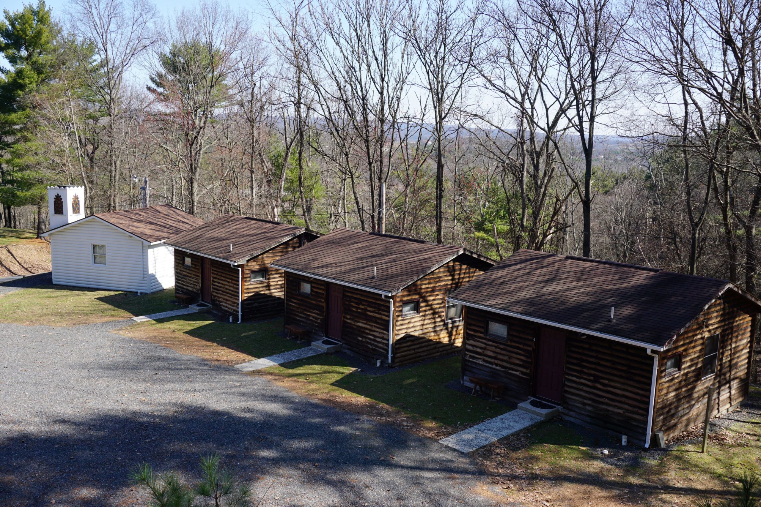 Row of small wood buildings along a paved road.