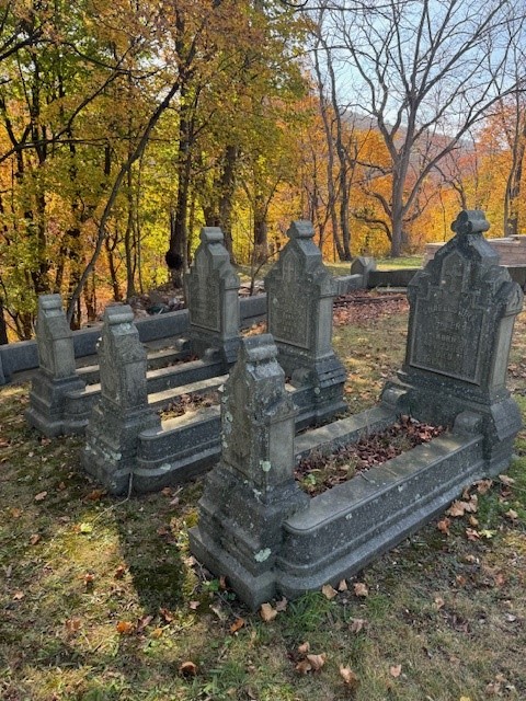 Three identical grave markers in a row on a hillside.