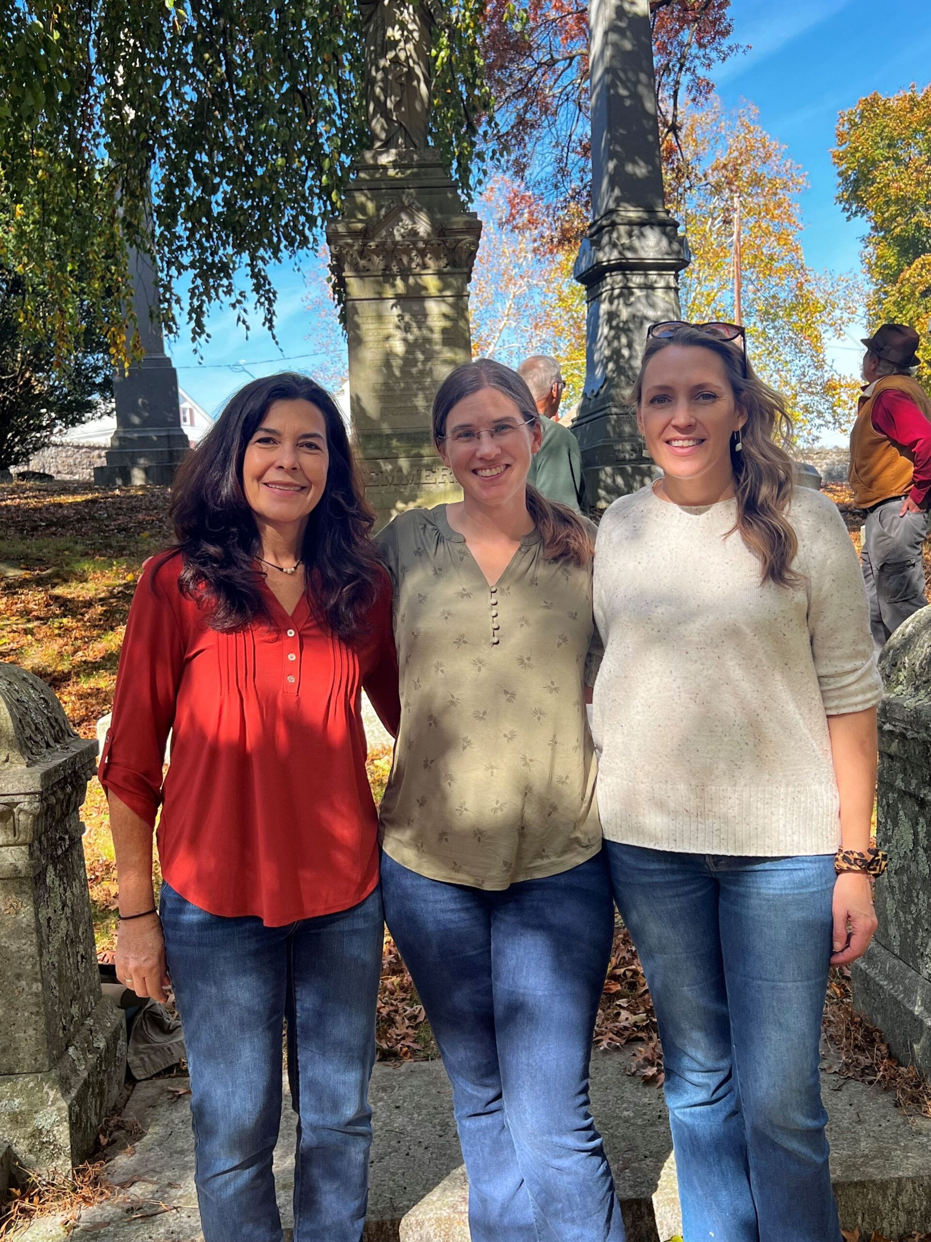 Three women standing outside on a sunny day.