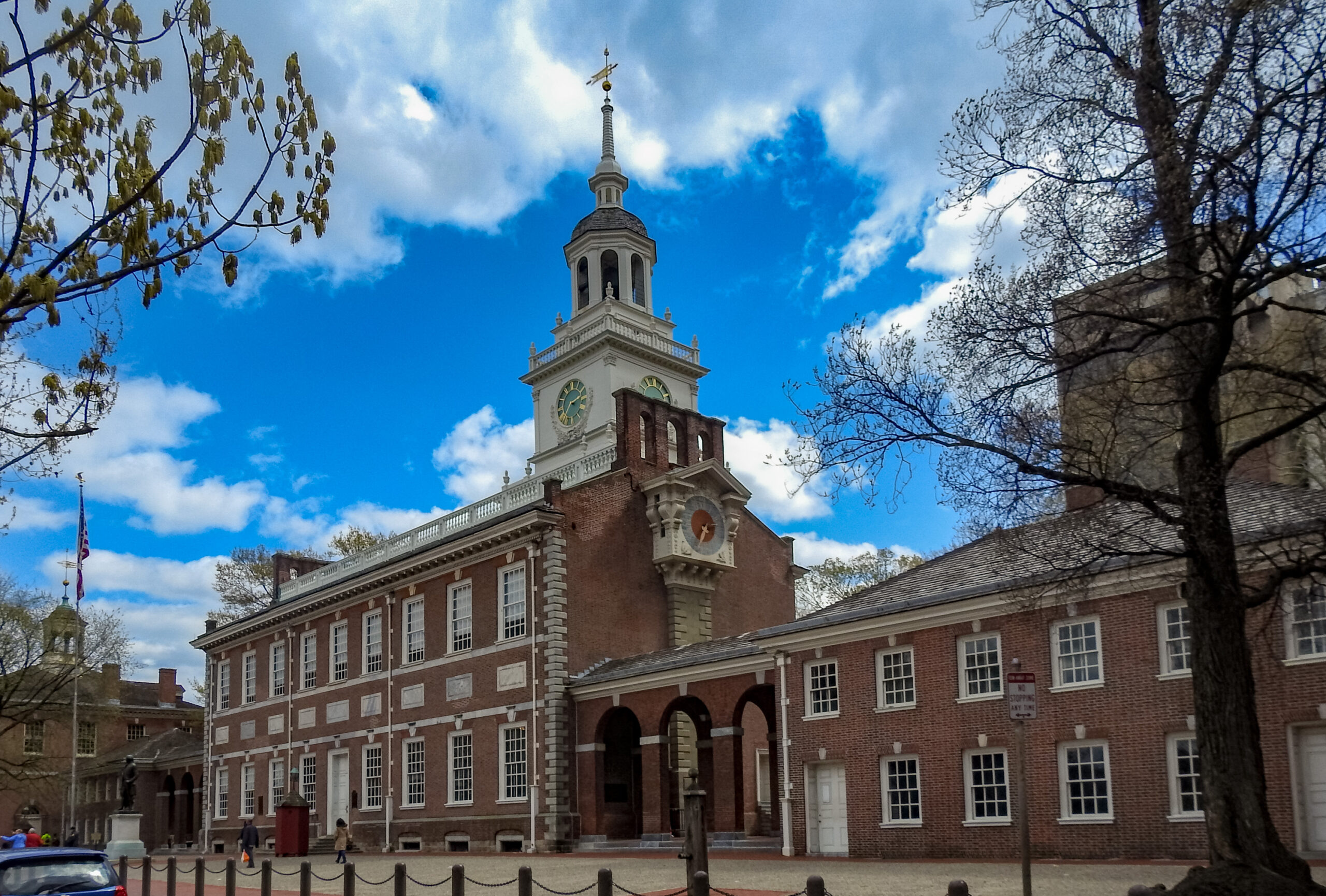 Large brick building with many windows and very tall wood steeple.