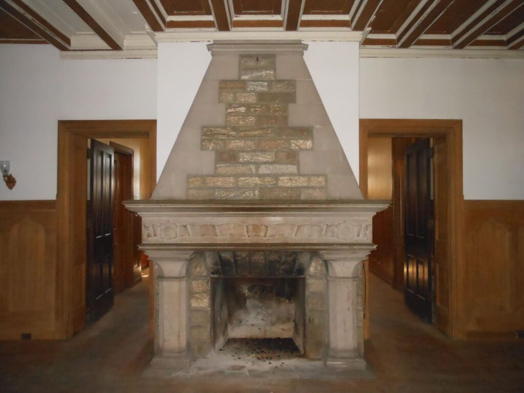 Large stone and concrete fireplace on a wall between two open doors.