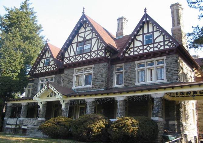 Large three story stone building with many rooflines and decorative features.