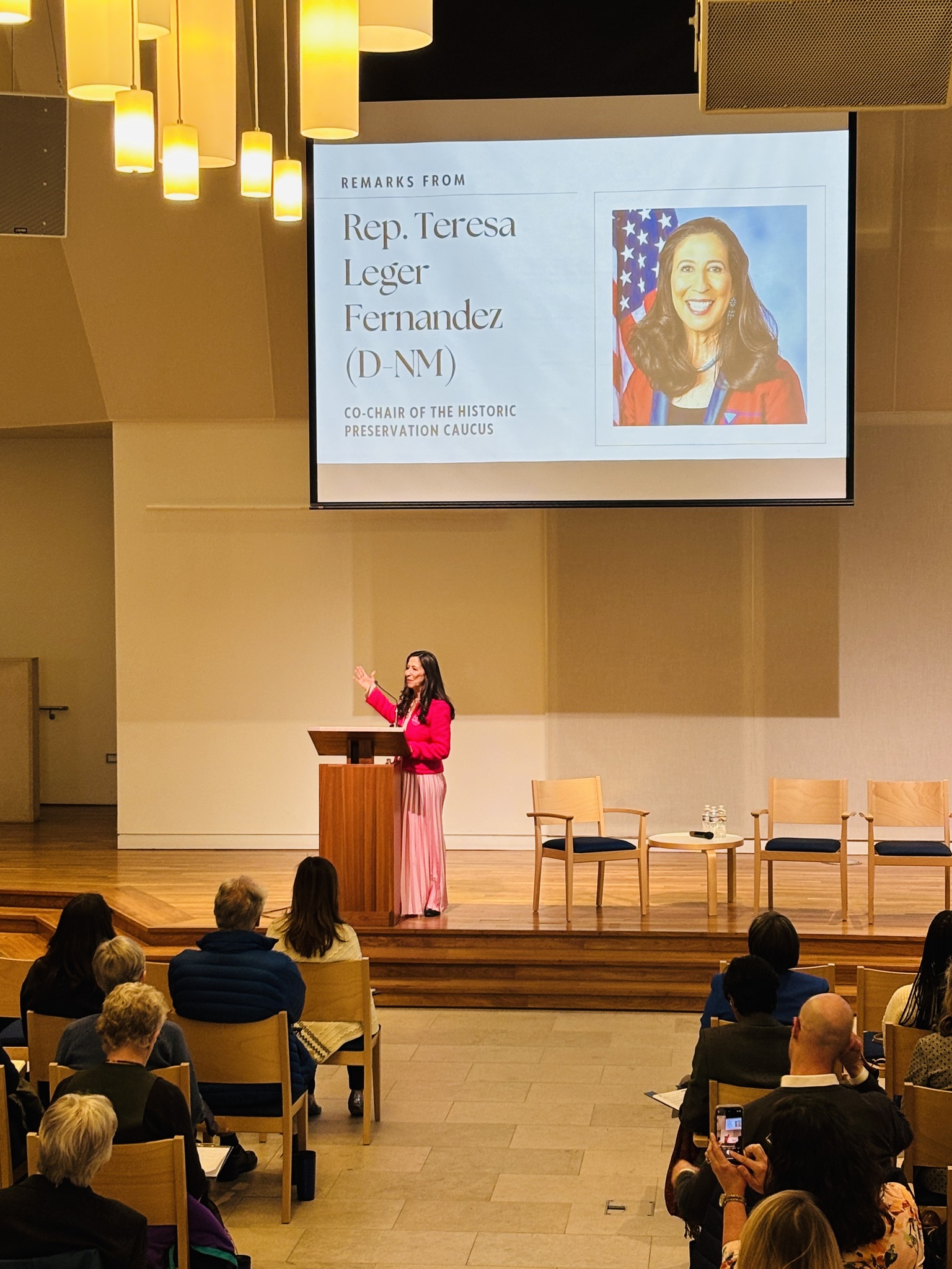 Woman stands at a podium on a stage.