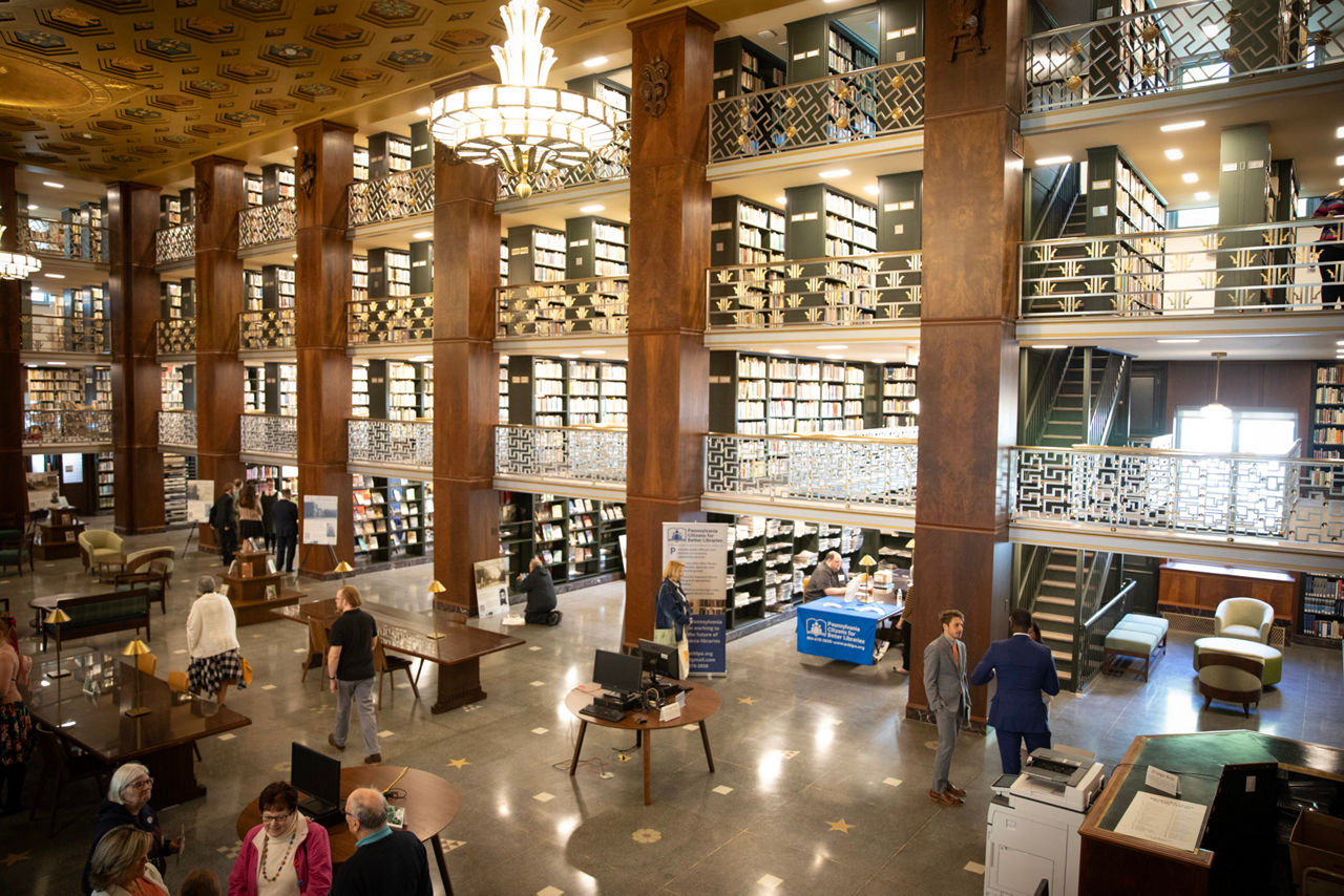 Large four-story room with an open center and floors with stacks of library books on the outer walls.