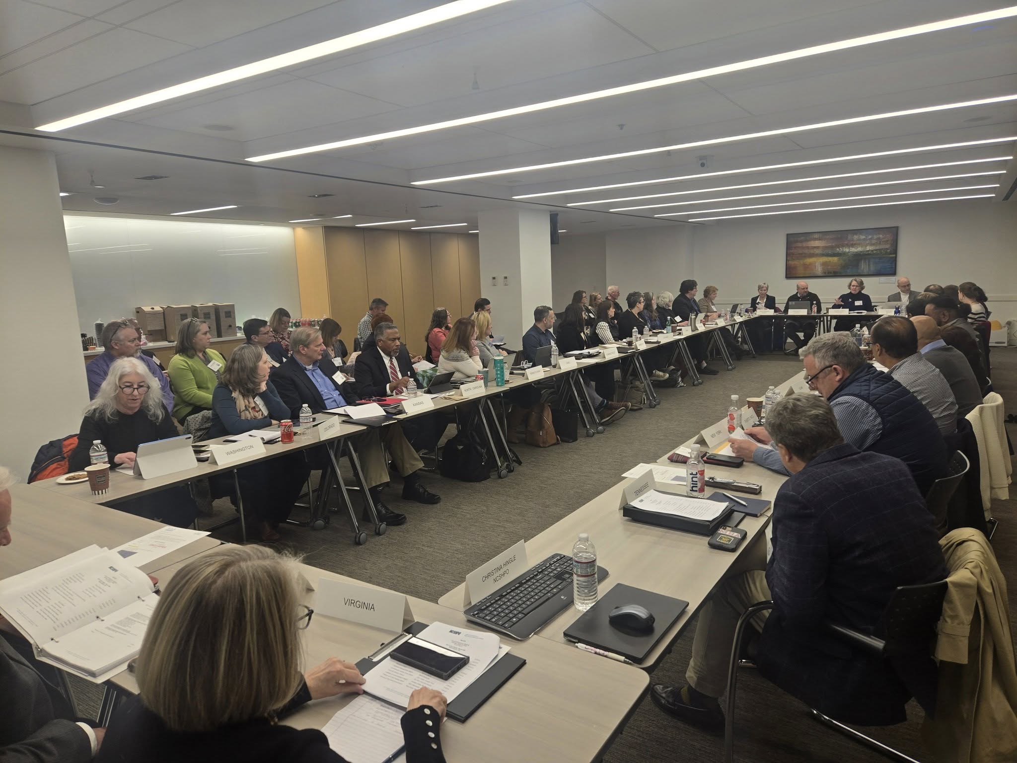 Large group of people sitting at tables in a room.