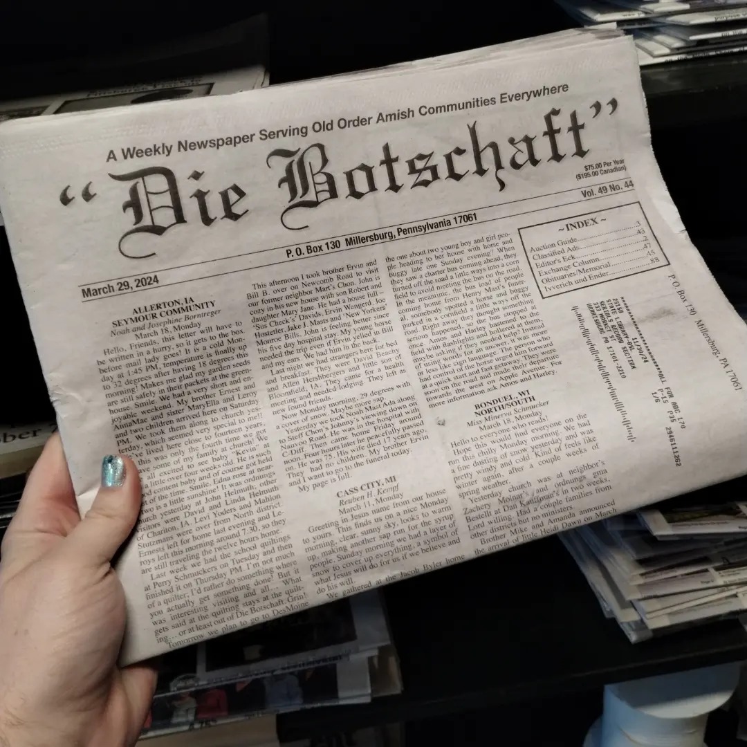 Hand holds folded newspaper from 2024.