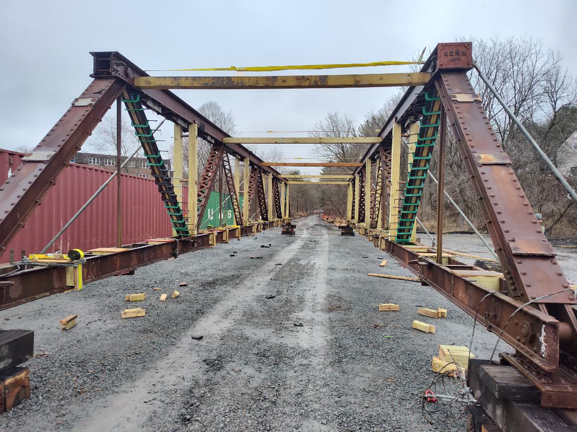 Metal truss bridge with wood braces and brackets.