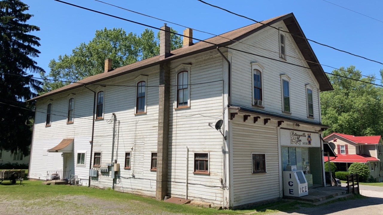 Long two-story wood frame building with many windows, a gable roof, and storefront window.