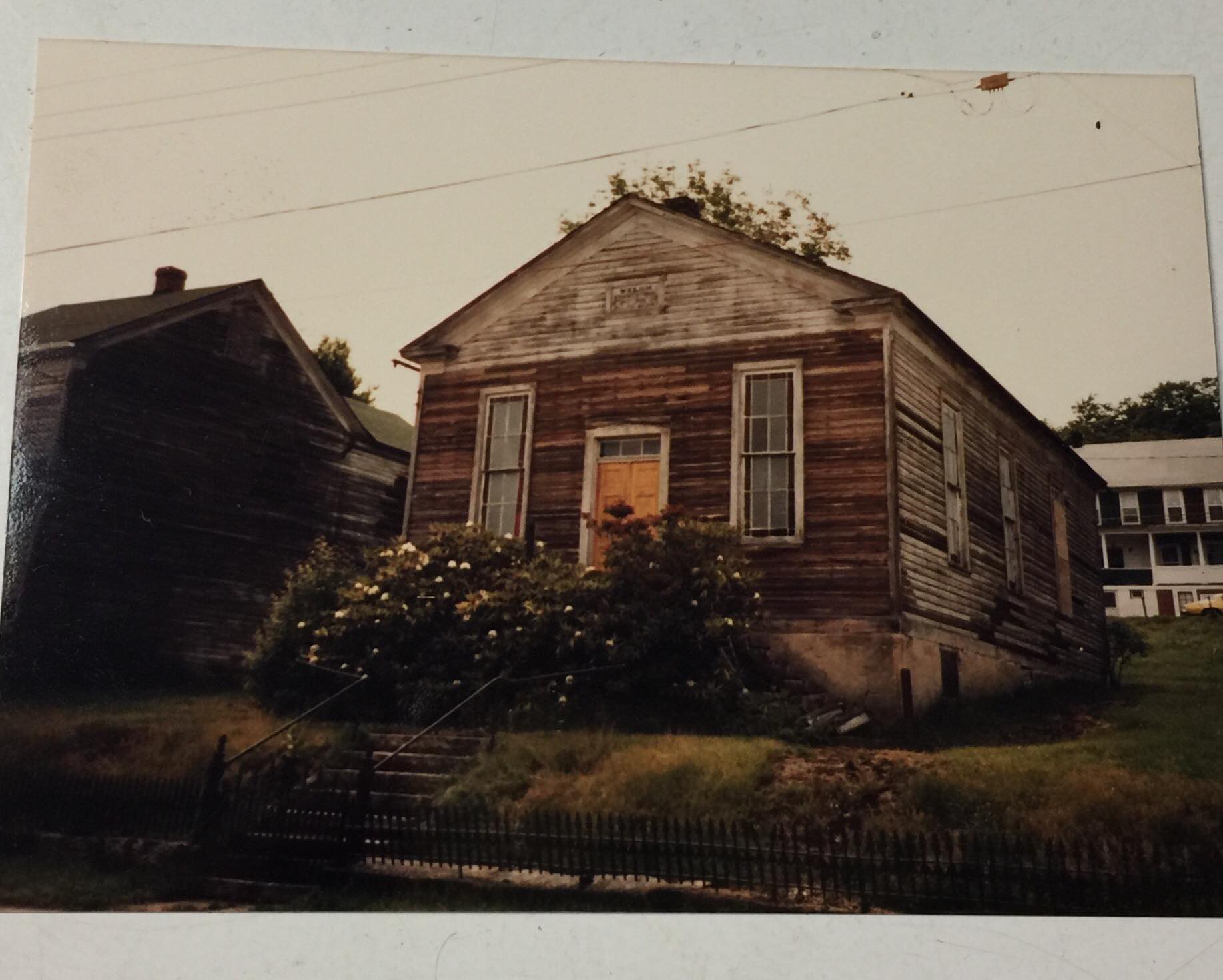 Small, one-story wood frame and wood clapboard building with windows and gable roof.