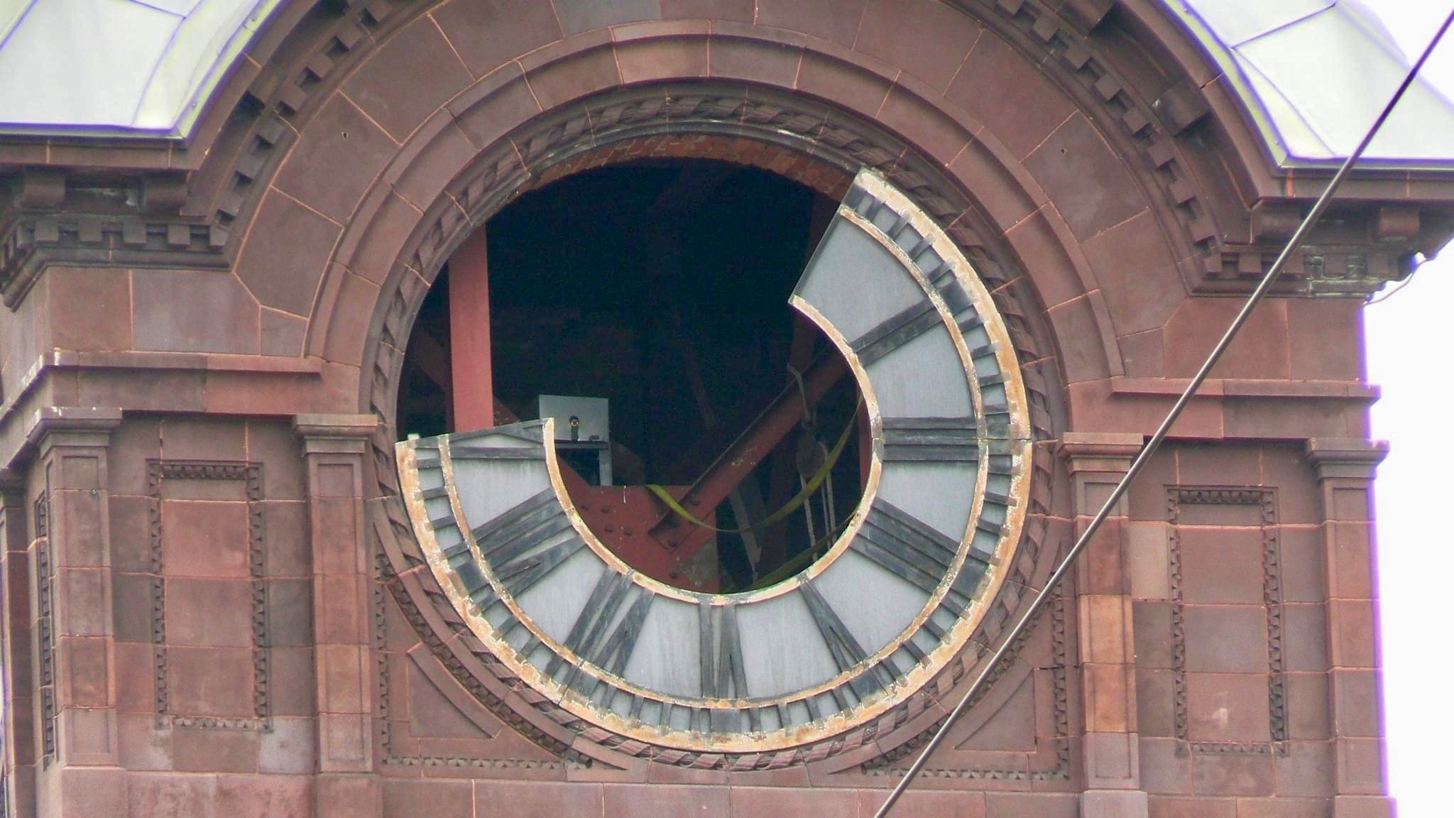 Masonry detailing in the steeple surrounding a glass clock face that has been partially removed.