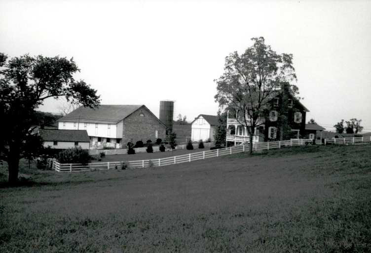 Farmstead surrounded by fields and includes house, two small outbuildings, and a large stone barn.