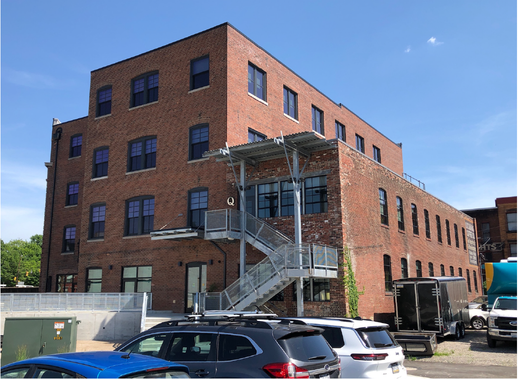 Large 4-story brick building with many windows along each floor in an urban setting.