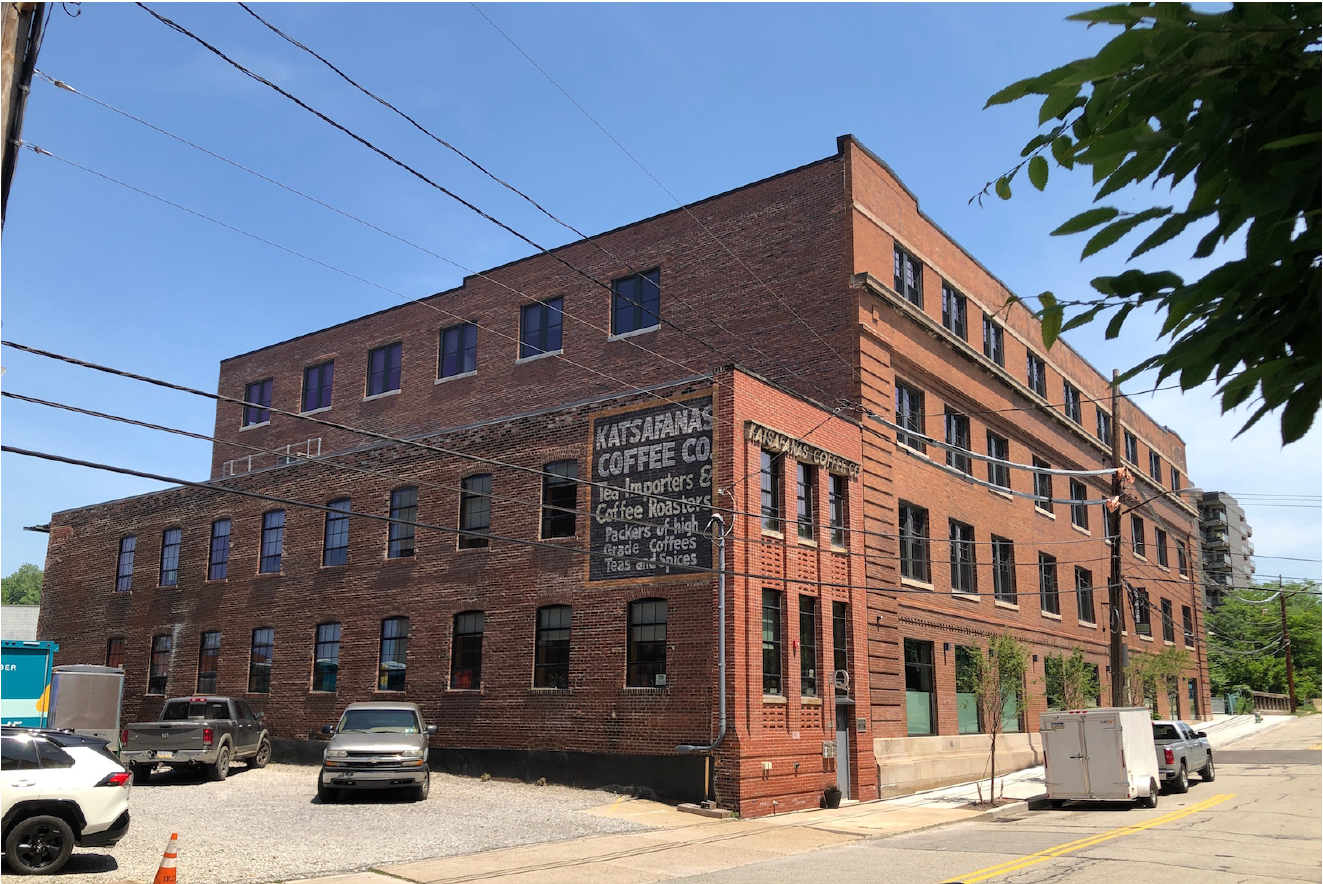 Large 4-story brick building with many windows along each floor in an urban setting.