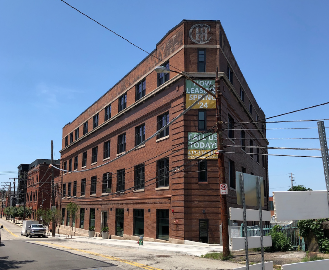 Large 4-story brick building with many windows along each floor in an urban setting.