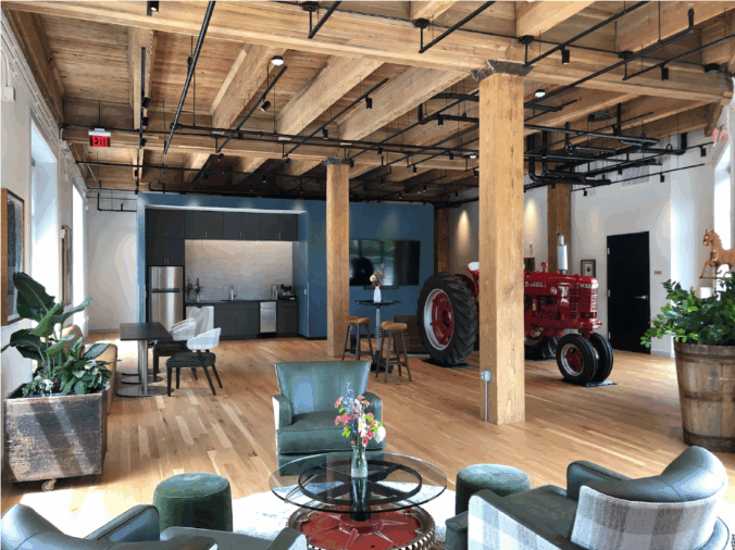 Interior room with furniture, a red tractor parked in a back corner, and wood columns and ceiling.