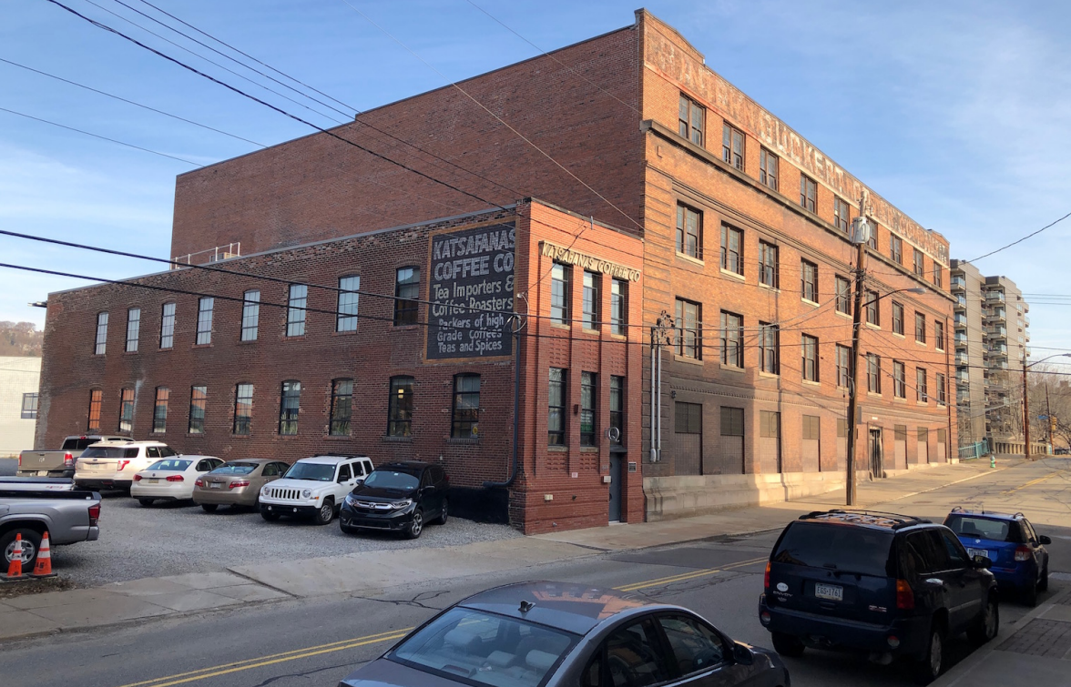 Large 4-story brick building with many windows along each floor in an urban setting.