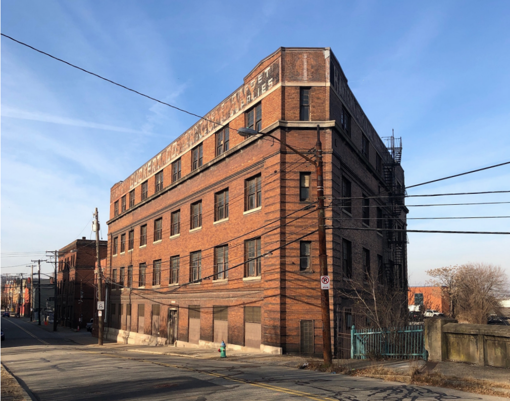 Large 4-story brick building with many windows along each floor in an urban setting.