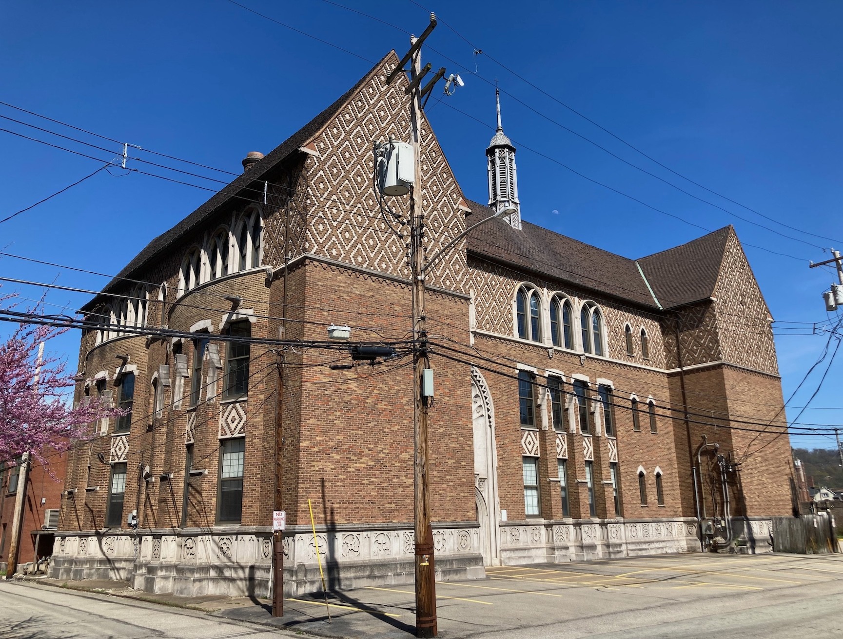 Three story brick building with decorative brick work at third floor and below windows and decorative stone band at the bottom of the walls.