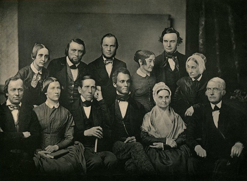Black and white image of 12 people arranged in two rows, seated in the front and standing the back.