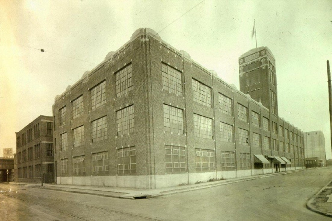 Brick industrial building with very large metal windows in an urban setting.