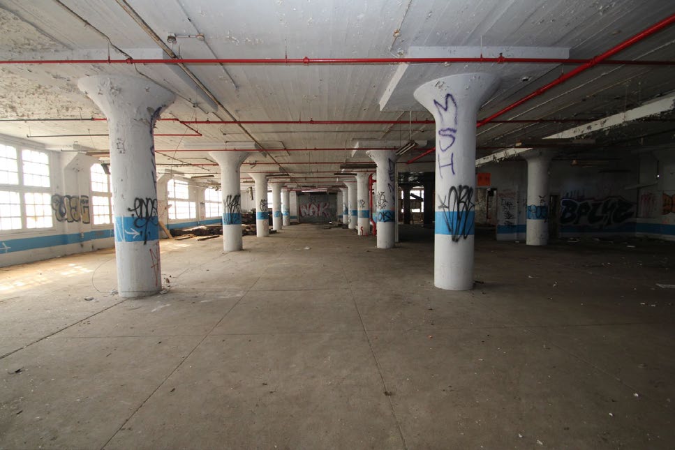 Open floor with large windows and concrete columns.