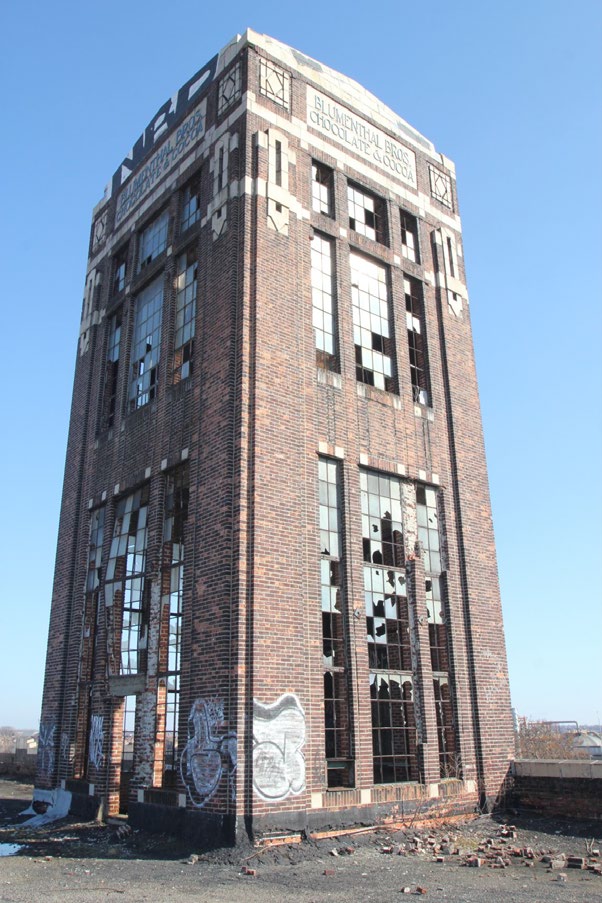 Tall, narrow brick tower with large broken windows and the words "Blumenthal Bros. Chocolate and Cocoa" at the top.