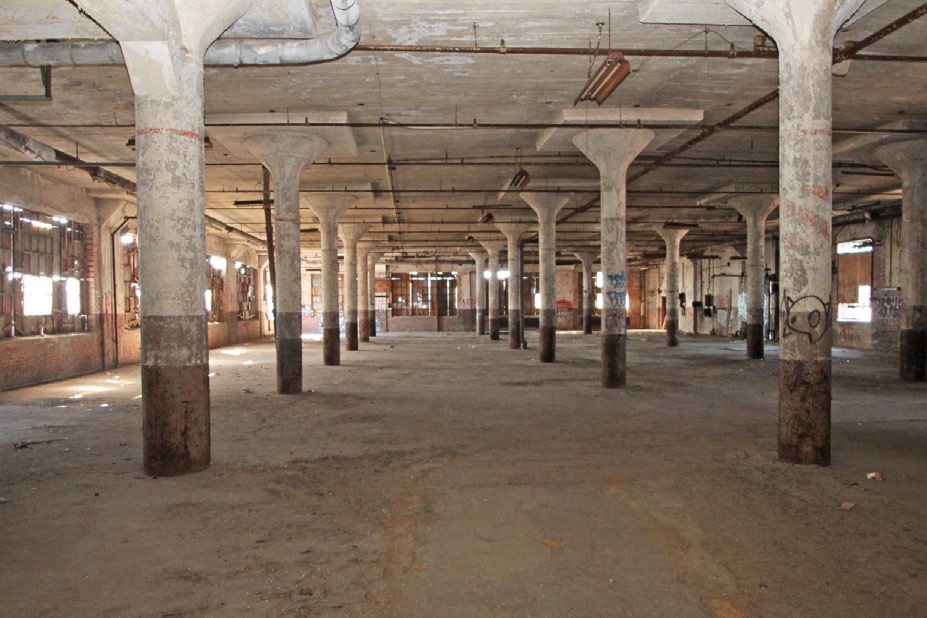 Open floor with large windows and concrete columns.